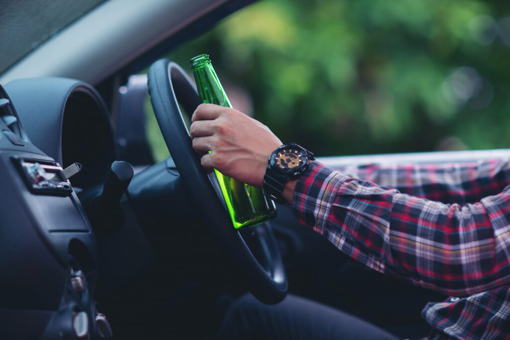 What is the permissible level of alcohol content for drivers in Ukraine? - asian man holds beer bottle while is driving car